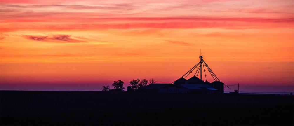 Outline of a grain bin during a sunset
